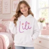 Personaliziran bel otroški pulover Lili z ročno vezenim imenom in rožicami na deklici